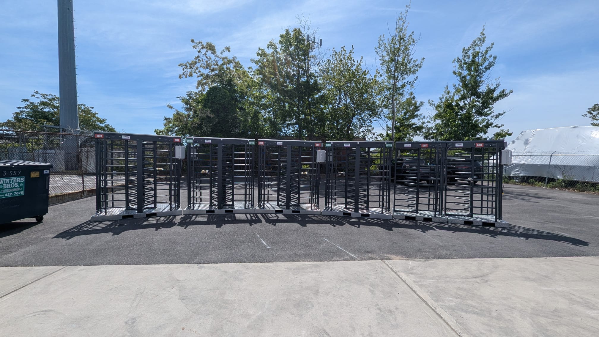 Six tandem full-height turnstiles, on a parking lot, awaiting transport.