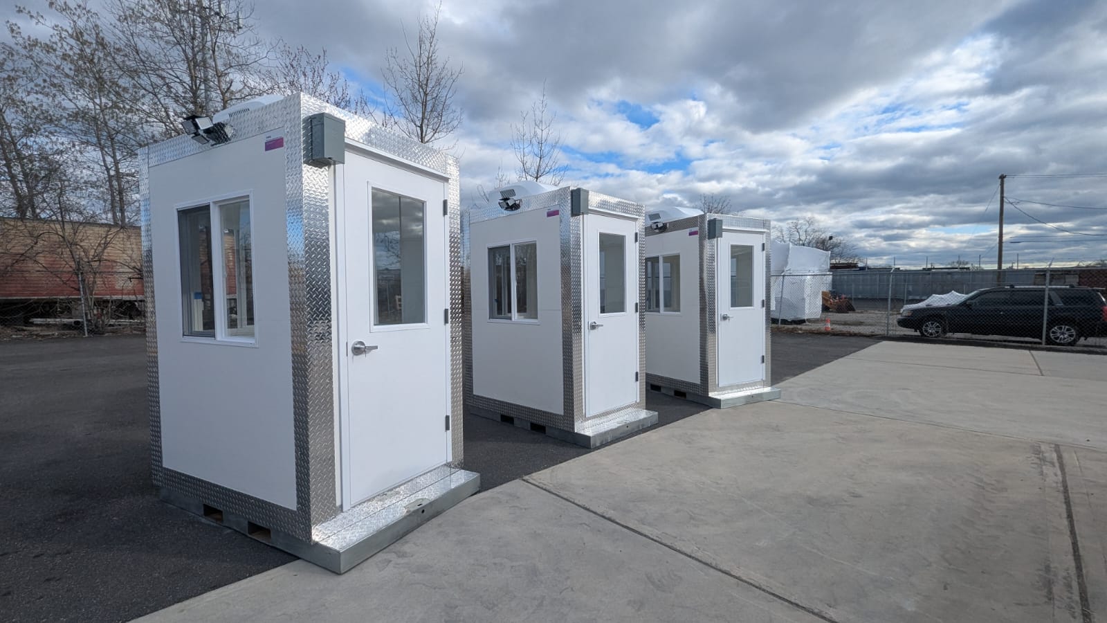 Three guard booths on a parking lot, waiting to be delivered to a new project site.